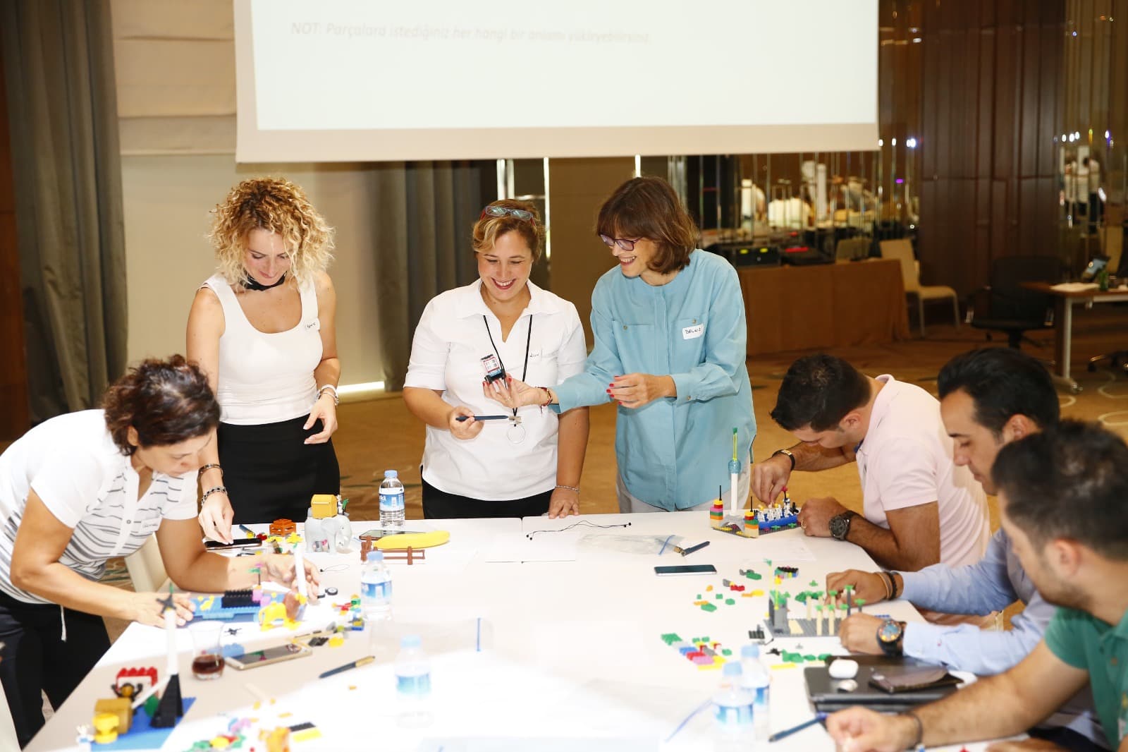 Participants and facilitators gathered around a table of LEGO models