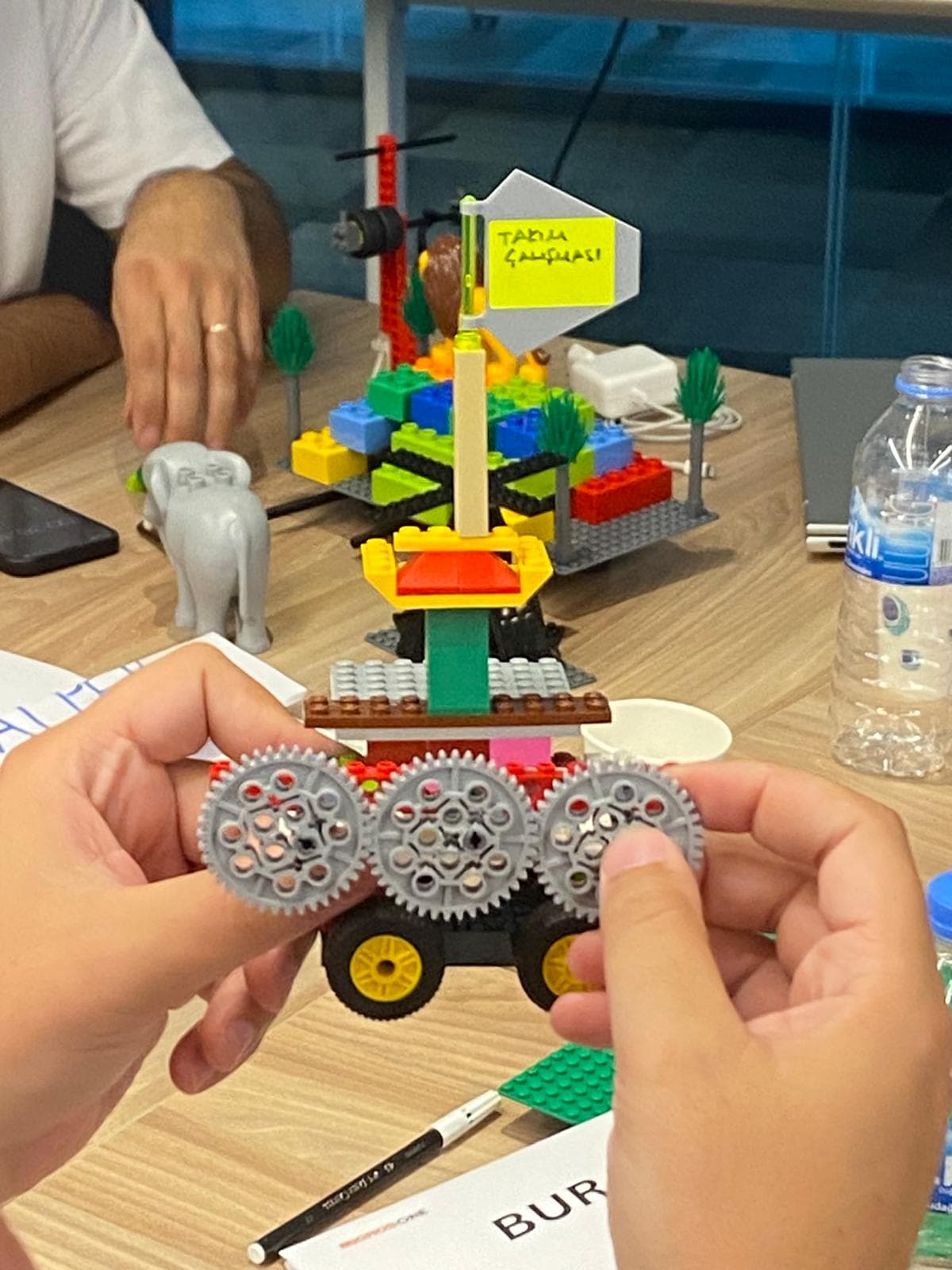 A participant holding up a geared model built around the theme of teamwork